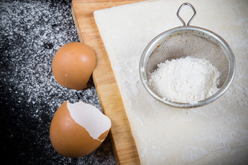 Set for home baking on a black background with flour. Dough, boa