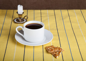 Cup of tea with biscuits and retro style candle on the striped y