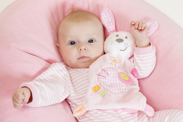 portrait of three months old baby girl with a toy