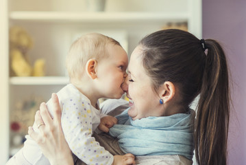 Young mother holding her cute little baby daughter in her arms