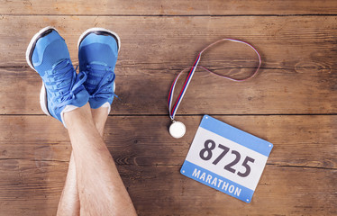 Legs of a runner, medal and race number on a wooden background