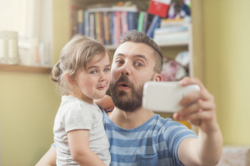 Young father with his cute little daughter taking selfie