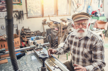 Senior man carving letters into marble plaque