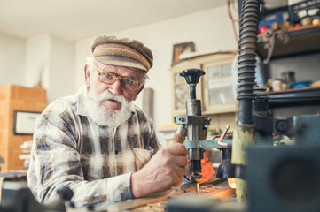 Senior man carving letters into marble plaque