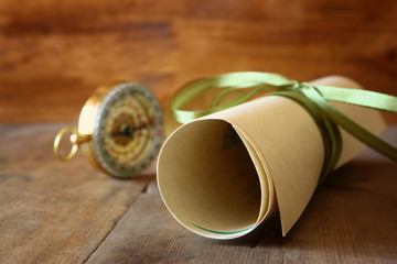old parchment and antique compass on wooden table
