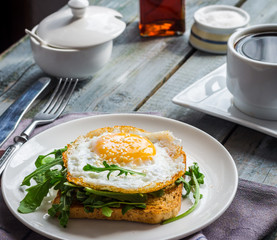 crispy toast with a fried egg and fresh arugula, a cup of coffee