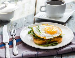 crispy toast with a fried egg and fresh arugula, a cup of coffee