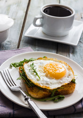 crispy toast with a fried egg and fresh arugula, a cup of coffee