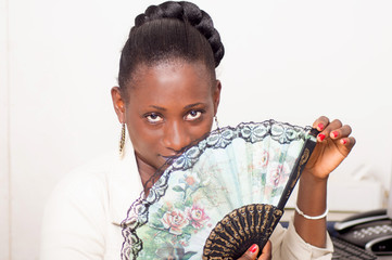 jeune femme africaine à son tenant dans la main un éventail .