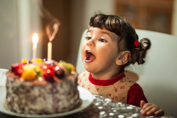 little girl blows out the candles on the cake