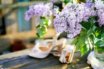 Bouquet of lilac on soft background with bride's shoes