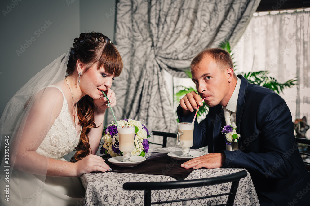 Wall mural bride and groom in luxurious restaurant drink a cup of coffee