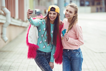 Hipster girlfriends taking a selfie in urban city context -