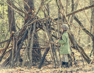 ittle cute girl builds a hut in the woods