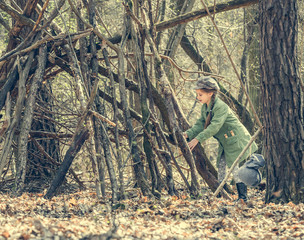 ittle cute girl builds a hut in the woods