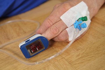 Hand eines Patienten mit Puls Oxymeter und Infusionsschlauch