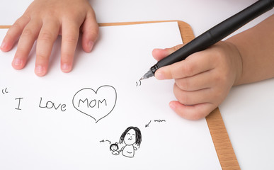 Preschool age child writing " I love mom " on white paper