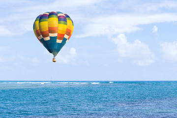 Fototapeta na wymiar Hot air balloon over ocean and clouds blue sky