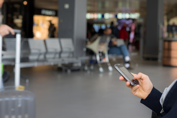 Waiting in airport terminal using phone