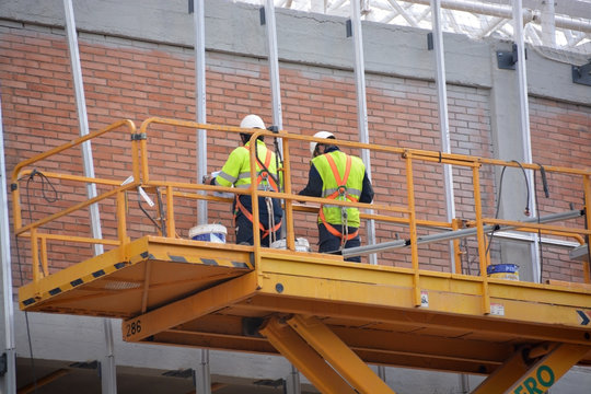 obreros trabajando encima de un andamio