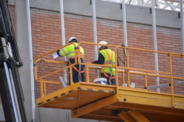 obreros trabajando encima de un andamio