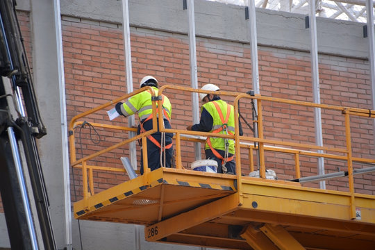 obreros trabajando encima de un andamio