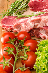 Raw meat with vegetables and spices on wooden background