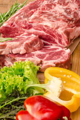 Raw meat with vegetables and spices on wooden background