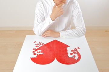 悩みながら赤いハートマークを創作している日本人男性