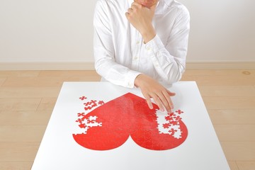 悩みながら赤いハートマークを創作している日本人男性