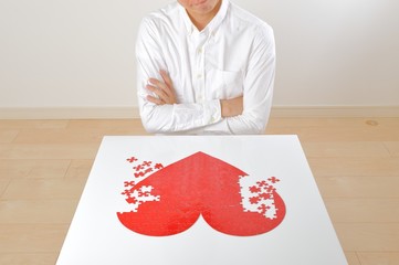 悩みながら赤いハートマークを創作している日本人男性