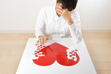 悩みながら赤いハートマークを創作している日本人男性