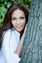 Pretty brunette girl next to a tree