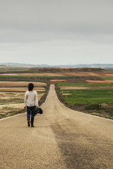 Woman walking alone in a country road - 82769680