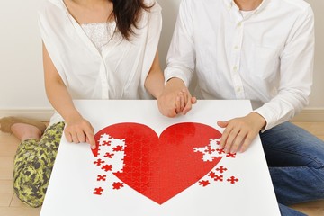 仲良く赤いハートのパズルゲームをしている日本人カップル