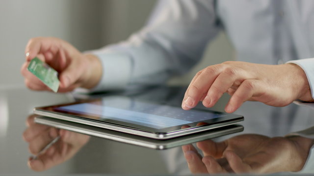 Man inserting credit card number on tablet PC, online banking
