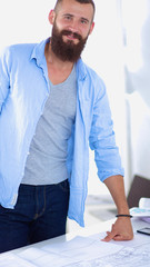 Obraz premium Portrait of male designer sitting on a table with blueprints