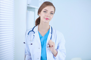 Woman doctor is standing near window with crossed arms,isolated