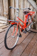 Fototapeta na wymiar Vintage red bike against the old wooden home, Thailand.