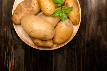 Raw potatoes on wooden plate
