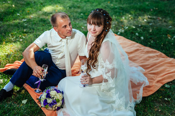 couple just married sitting in park green grass with bouquet of