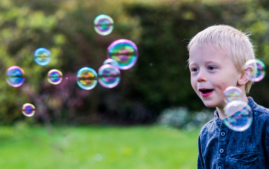 One Little boy blows soap bubbles in the garden on a summer day