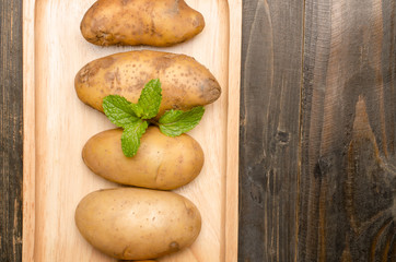 Raw potatoes on wooden plate