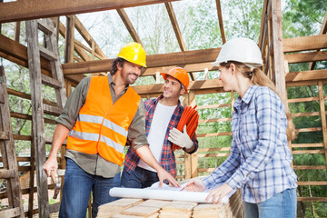 Happy Workers Discussing Over Blueprint At Site