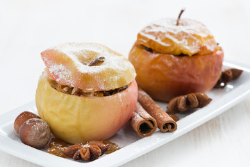 baked stuffed apples on a plate on white wooden table, close-up