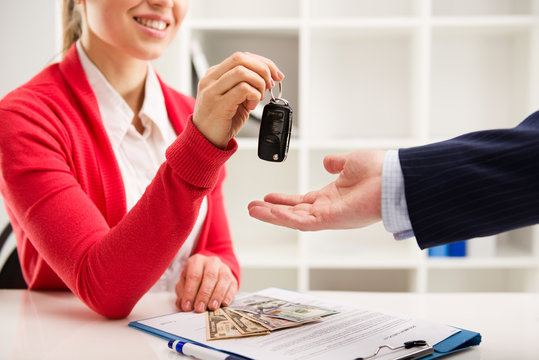 Rental contract. Woman automotive dealer offering key to buyer
