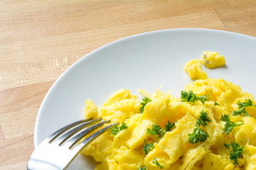 scrambled eggs with parsley garnish on a white plate