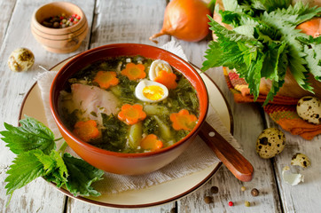 Nettle soup with eggs and carrot in the bowl on the table