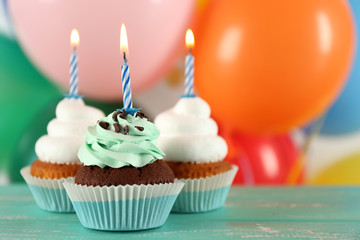 Delicious birthday cupcakes on table on bright background