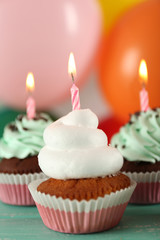 Delicious birthday cupcakes on table on bright background